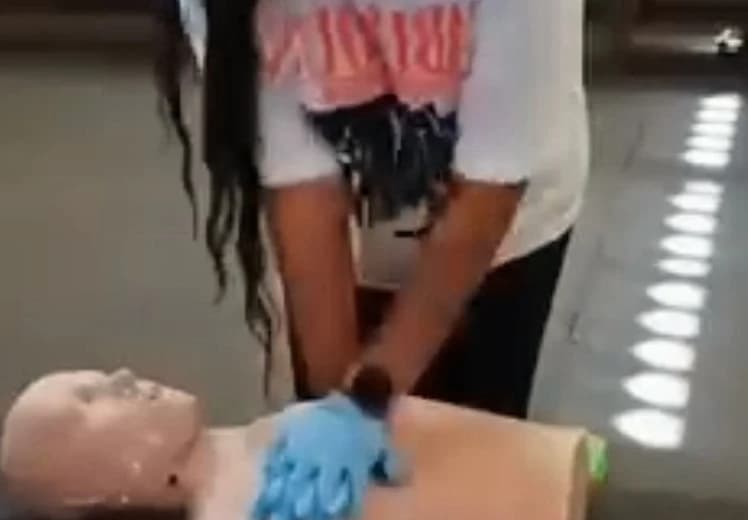 Student performing chest compressions on an adult CPR manikin during hands-on AED and CPR training
